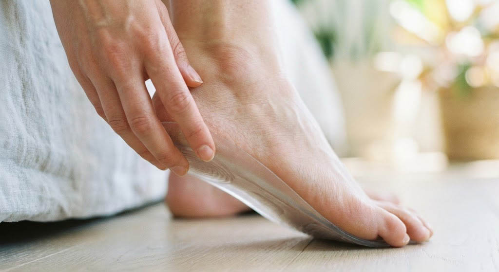 Application d'une semelle orthopédique en gel sous le talon d'un pied nu pour soulager une pathologie du pied